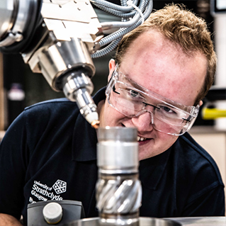Man in safety goggles looking machine