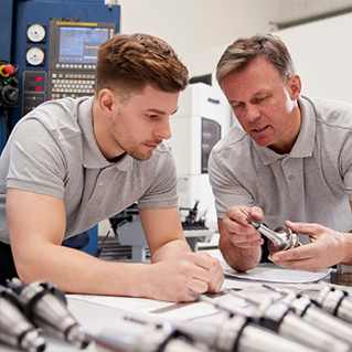 Two men in factory discussing a renewable part